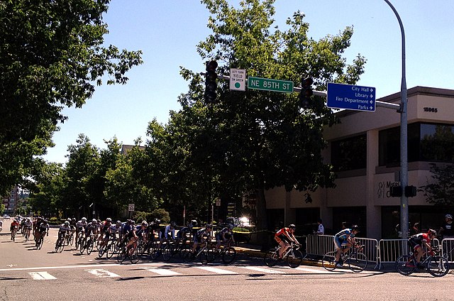 A large group of bicyclists turn onto NE 85th Street in Redmond, WA, during Redmond Derby Days