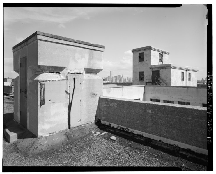 File:Roofscaps detail, showing reinforced concrete observation post (left) and penthouse for elevator machinery (right). Manhattan skyline in background. Representative interior view, HAER NY,24-BROK,56-12.tif