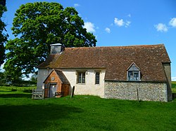 A small simple church, largely rendered with a tiled roof, a brick porch, and a bellcote at the west end