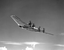 Photo en noir et blanc d'une aile volante XB-35 en vol, dotée de plusieurs moteurs à hélice.