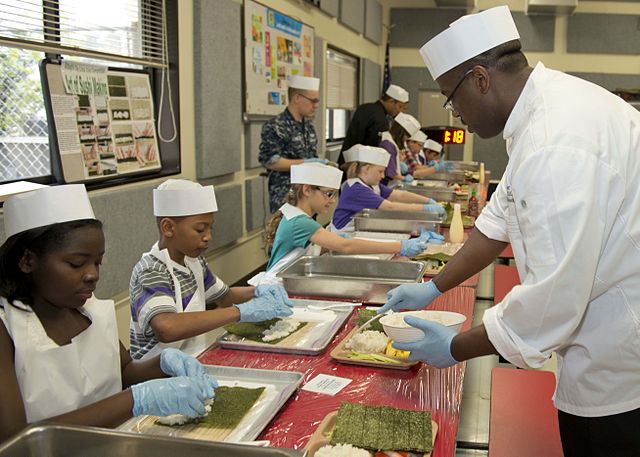 American students learning how to make and roll sushi