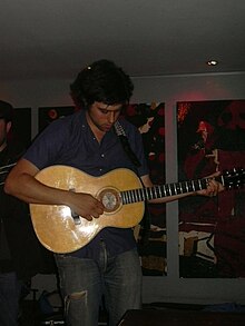 Young man playing an acoustic guitar with a focused expression