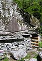 Adding a dry stone wall to convert the space under a large rock into a functional building near Bignasco, سوئیس