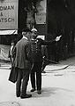 Polis memuru, 20 numaralı Goldman & Salatsch şapka dükkanının önünde yoldan geçen bir kişiye brifing verir.