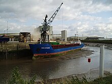 The Fehn Cartagena unloading a cargo of stone while moored on a mudbank in The Haven, opposite the Black Sluice