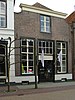 Huis met lijstgevel met ingezwenkte zijkanten en met schuiframen en winkel-ingangspartij uit de bouwtijd