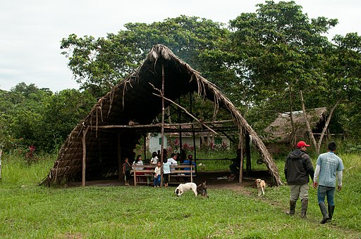 Casa comunal tradicional como sala de reuniones en una comunidad Huaorani moderna 