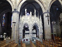 Foto di una tomba monumentale neogotica in pietra bianca nella navata di una chiesa