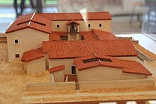 Foto van een maquette van een Romeins huis waar een zuilengalerij een vloer ondersteunt.