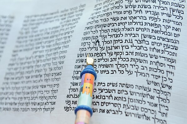 The opening chapter of a hand-written scroll of the Book of Esther, with reader's Torah pointer