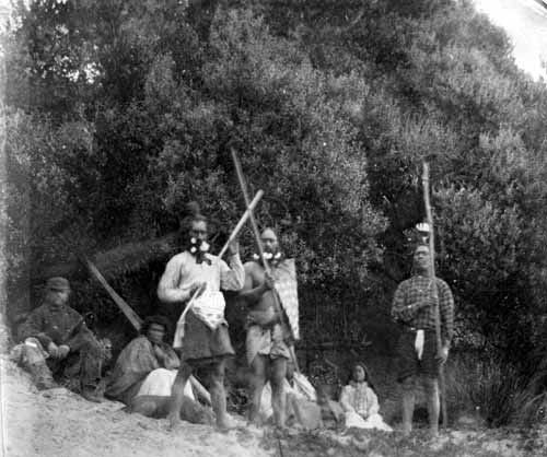 Moriori people in the late 19th century: these three men (standing) are wearing a mix of traditional and European clothing. They carry defensive staff