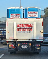 Rear view of a stake bed truck carrying chemical toilets.