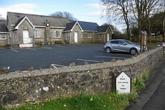 single storey stone building with car park in foreground