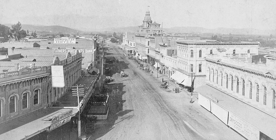 Main Street looking north from Temple, photo by T.E. Stanton, 1886. The Baker Block is the prominent building towards the back. Left side: Cosmopolitan Hotel, Farmers and Merchants Bank , Downey Block with Commercial Restaurant.