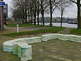 Outdoor benches at the area Marineterrein with a view through tree trunks; free photo Amsterdam, Fons Heijnsbroek, January 2022