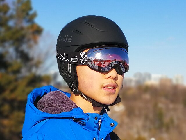 A skier is wearing ski goggles. He is also wearing a black helmet and a blue ski jacket.