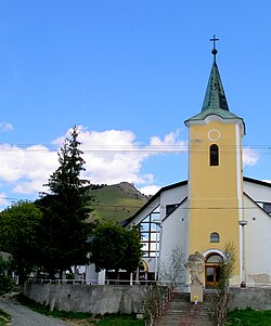 Gereja desa dengan reruntuhan Kamenicky hrad di latar belakang.