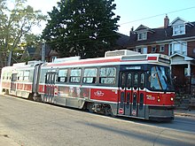 red, black and white streetcar with some houses in the background