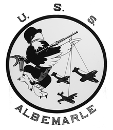 Insignia of Curtiss-class seaplane tender USS Alblemarle showing a helmeted eagle, armed with a 20mm. Oerlikon machine gun and a holstered .45 Pistol, dangling two PBY and one PBM, puppet-fashion, from one wing USS Alblemarle Insignia.png