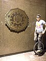 Unicyclist poses before a plaque of the United States Department of Justice (3356715415).jpg