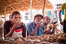 These Yawo men sit at a rural village market in Mozambique where usipa (dried fish) is being sold while they chow down on locally baked pao (bread) Usipa and Pao.jpg