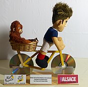 Cycliste réalisé avec 2 peluches pour enfant (doudou) de récupération (Olivier Giroud et petit singe) et un vélo réalisé notamment avec des disques optiques. Ceci a été réalisé en lien avec le Tour de France 2024, le Tour de France Femmes 2024 et le Tour Alsace 2024.