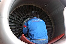 A Braathens employee working on a CFM International CFM56 turbofan engine