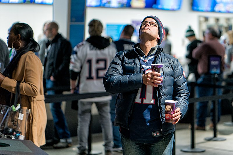 File:A Patriots fan with beer in hand pauses to observe the National Anthem from a monitor at Super Bowl LII, Minneapolis MN (39407948184).jpg