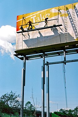 Billboard workers painting advertisement