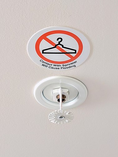 A sign warns hotel guests not to hang items from fire sprinklers