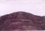 Large rock with symbols cut into it and foundations of buildings.