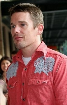 A Caucasian male with brown hair and stubble, wearing a red shirt.