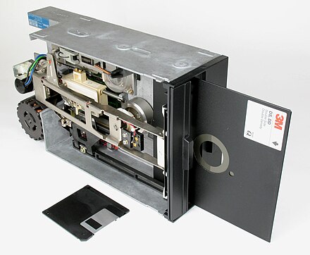 8-inch floppy disk, inserted in drive,(3½-inch floppy diskette, in front, shown for scale)