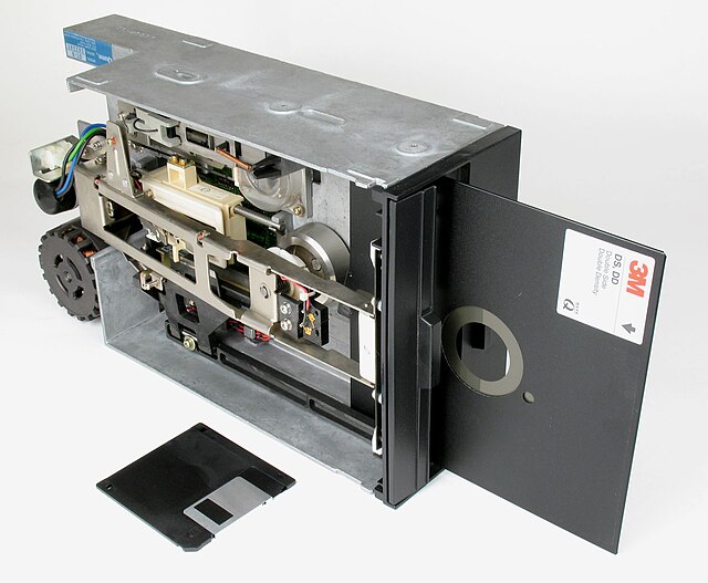 8-inch floppy disk, inserted in drive, (3½-inch floppy diskette, in front, shown for scale)