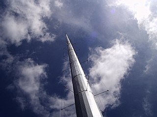 Folded unipole antenna with a solid metal mast surrounded by six skirt wires, held away by standoffs