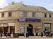 A beige-bricked building with a blue sign reading "GREAT PORTLAND STREET STATION" in white letters all under a blue sky with white clouds