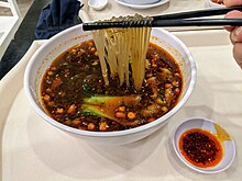 Hot and sour noodles topped with pork intestines, peanuts, and bok choy, a popular Sichuan street snack Hot and sour noodles with pork intestines.jpg