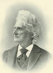 An old, monochromatic faded photograph of an elderly sharp-nosed, white-haired man wearing a suit, looking to the left.