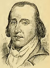 A man with dark, receding hair wearing a high collared white shirt and black jacket