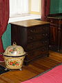 ;A night table or commode. (closed) The function of the night table was obvious, but here it was concealed behind false drawer fronts. This was a commode in both senses- Commode: (1) a chest of drawers wider than high (2) a night stool- a chamber pot holder- a potty for adults
