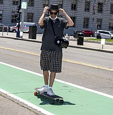 A skater cruising on his longboard Man skateboarding with a cool hat and mask.jpg