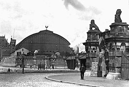 Foto en blanco y negro, escena callejera frente a la estación.