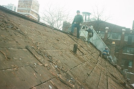 Roofers on a pitched roof in the United States conducting a roof tear-off