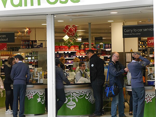 A Waitrose customer services partner serving a customer during the Christmas period at Putney