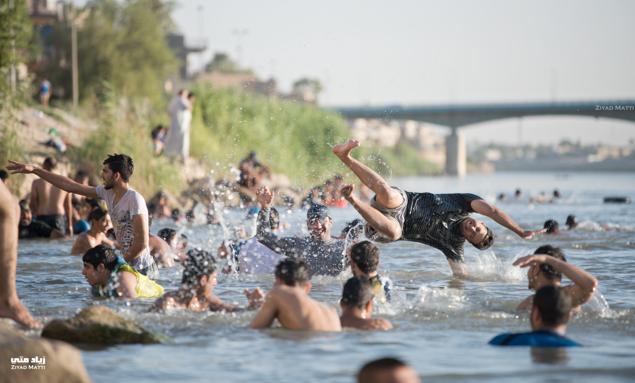 Young men having fun in Tigris River on a hot day.png