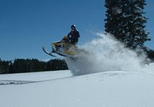 Foto van een Ski-Doo die van een sneeuwduin springt.