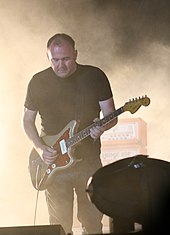 A picture of a man playing a guitar on a stage