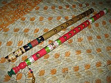 two colorful bamboo flutes on a bed