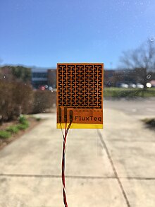 Heat flux sensor mounted on a window. Heat flux sensors can be used like this to determine the R-value or U-value of building envelope materials while they are still installed in buildings. FluxTeq PHFS01 Heat Flux Sensor.jpg