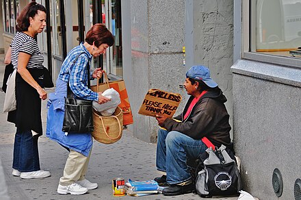 Vrouw die geld geeft aan een dakloze man